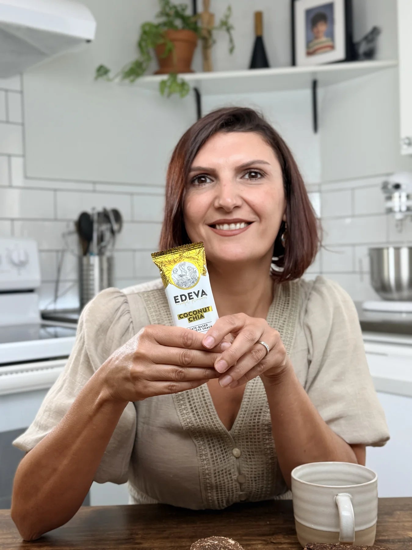 Souja, EDEVA founder, holding a Coconut Chia Date Bar in her kitchen
